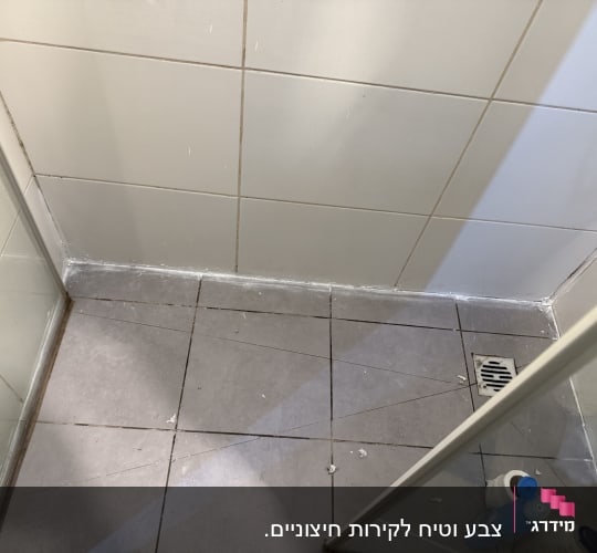 רצפת מקלחת עם אריחים ובקבוקי ניקוי בפינה